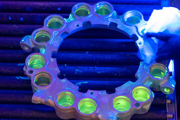 Aerospace NDT Inspection Showing Fluorescent Penetrant Testing of Brake Assembly. UV illumination reveals surface discontinuities in aircraft brake piston housing during quality control