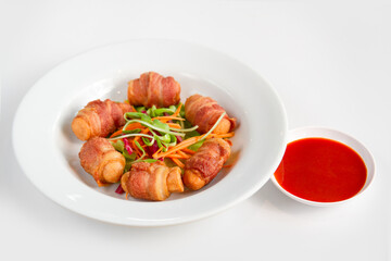 Fried sausages wrapped in bacon serve with mix vegetable, chili sauce and ketchup on white background
