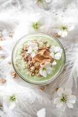 Healthy green smoothie bowl topped with peanut butter and edible flowers, an artistic touch for any wellness lifestyle.