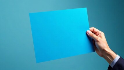 Obraz premium blue blank sheet for text in man's hand on blue background