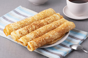 Delicious rolled pancakes on a plate on a grey textured surface in a cozy kitchen setting