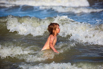 Kid swimming having fun and jumping in the waves of the sea. Summer kids vacation and healthy lifestyle concept.