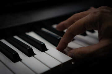 Fototapeta premium Close-up of male pianist's fingers pressing the black and white keys of an electric piano.