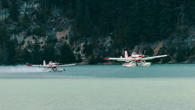 Two water bomber glides across a lake, collecting water for a fire