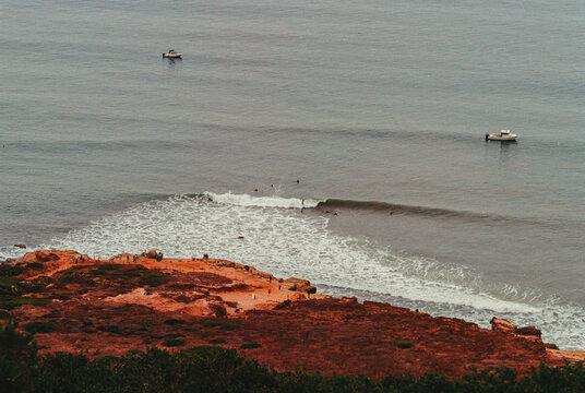 Aerial View of Cliffside Coastline with Boats in the Distance