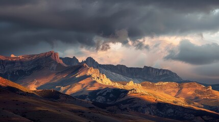 Naklejka premium Majestic Mountains Bathed in Sunset Light with Dramatic Clouds