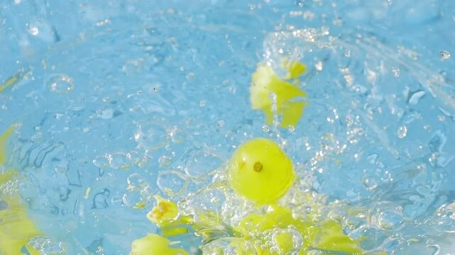 Fresh organic green grapes splashing into water in slow motion 300fps