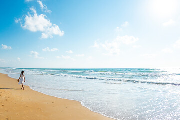 Happy beautiful young woman walking on the beach.Carefree girl walking along the beach on a sunny day.