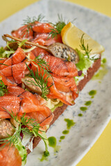 A vibrant and refreshing smorrebrod, a traditional Danish open-faced sandwich, topped with smoked salmon, fresh vegetables, herbs, and a creamy spread