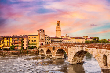 Famous Verona landmark. Ponte di Pietra Bridge over Adige river during colorful sunrise.