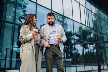 Business people talking and holding coffee outside office building