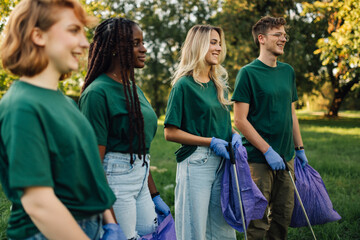 Volunteers collecting trash in park wearing matching shirts and gloves