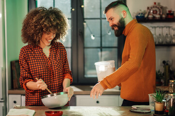 Couple making dough, mixing ingredients in kitchen, baking together at home