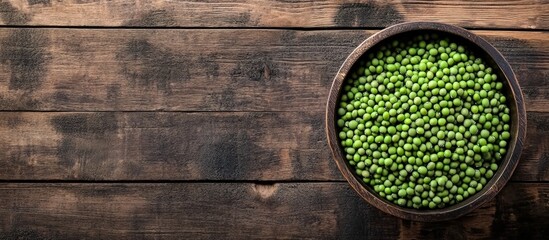 Fresh green peas in a wooden bowl on rustic wooden background with ample copy space for text insertion