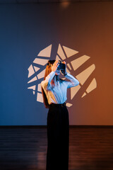 Woman exploring virtual reality through VR glasses in a vibrant digital space with artistic...