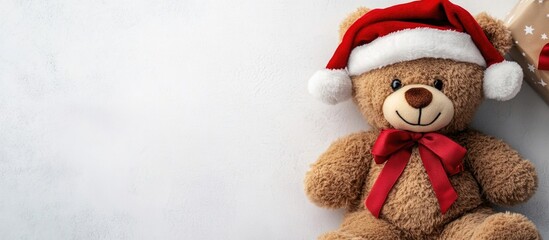 Teddy bear wearing Santa hat with red bow on white background for Christmas decorations with copy space