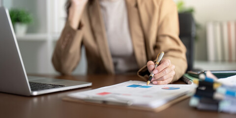 Businesswoman analyzing financial charts and graphs, focusing on reports during a work session