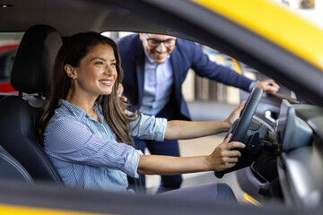 Happy woman with car dealer in auto show or salon. Car Sales Manager Showing Auto To Lady Buyer...