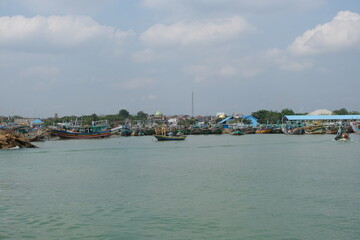 Fototapeta premium Scenic View of Traditional Wooden Boats Docked at a Bustling Coastal Harbor Under a Blue Sky