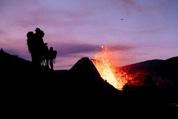 black silhouettes of people watching an eruption in Iceland