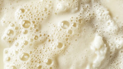 Frothy creamy cold milk texture close-up for cappuccino espresso with soft beige tones and ample negative space for text overlay.