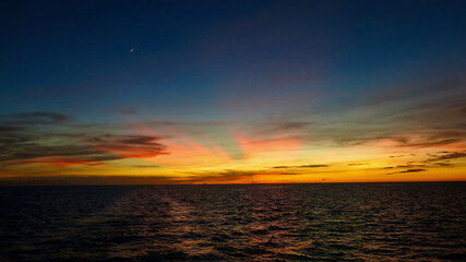 Fototapeta premium Sunset over the sea. View of the rays of the setting sun over the surface of the ocean. Sunset sea.