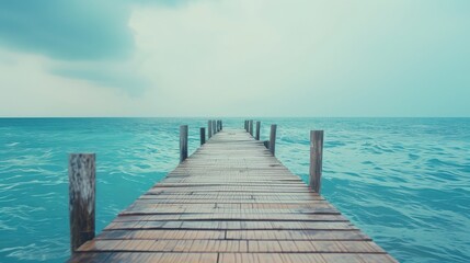 Fototapeta premium Wooden pier stretching towards a serene ocean under soft light