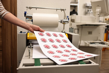 Woman with printed flower stickers indoors, closeup. Printing house