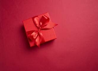 Red gift box with a red bow on a red background, element for design with copy space for text or...