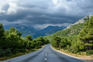 Naklejka premium Mountain road winding through scenic nature with green hills and clouds in the sky