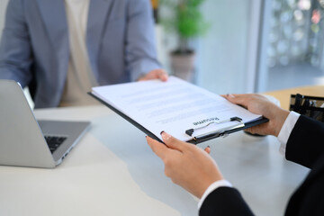 Close up of a candidate handing over resume to the interviewer during formal job interview