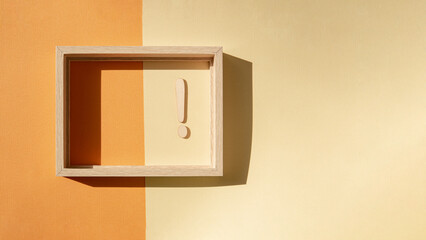 Abstract banner with an exclamation mark in a wooden frame on an orange-yellow background. An abstract concept.
