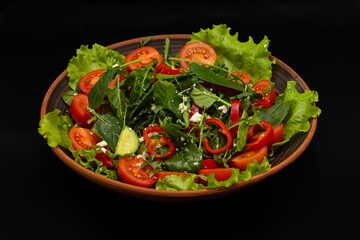 Greek vegetable salad with feta cheese, tomatoes, cucumbers, onions, olive oil on a black background