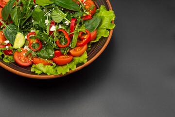 Greek vegetable salad with feta cheese, tomatoes, cucumbers, onions, olive oil on a black background
