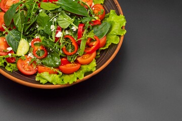 Greek vegetable salad with feta cheese, tomatoes, cucumbers, onions, olive oil on a black background