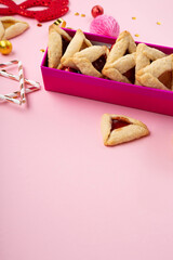 Hamantaschen Cookies, Red Carnival Mask, Noisemaker on Pink Background. Purim Celebration, Jewish Carnival Holiday Concept.