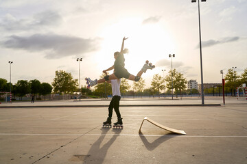 Rollerblading duo performing an aerial stunt with a ramp at sunset