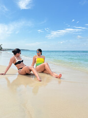 Fototapeta premium Two young women relaxing on tropical beach enjoying summer vacation