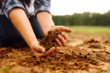Close up of male hands touching dry ground in an agricultural field. Concept of agribusiness.