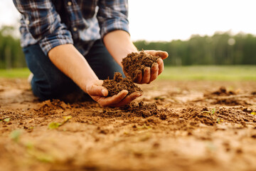 Close up of male hands touching dry ground in an agricultural field. Concept of agribusiness.