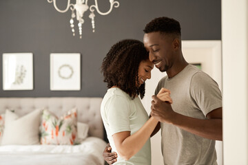 Smiling young multiracial couple dancing together in their bedroom