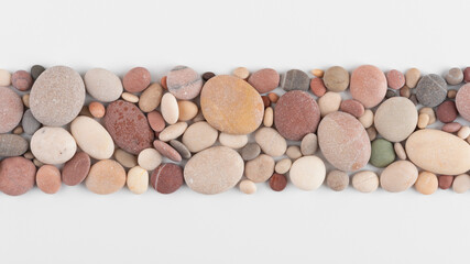 Top view of smooth, multicolored pebbles arranged on a white background