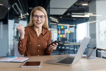 Portrait of successful woman sitting at desk inside office at workplace. Mature businesswoman...