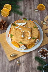 Fototapeta premium New Year's cake, Christmas decorated with gingerbread and oranges on a wooden background. Homemade honey cake.