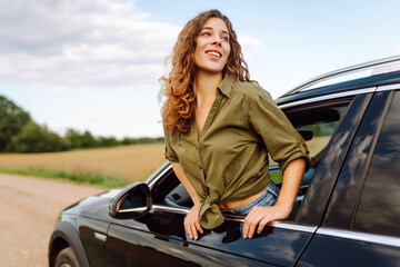 Young woman travelling by car or camper van, open window breathe fresh air of countryside. Travel...