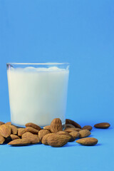 Almond milk, natural almonds scattered next to the glass cup.