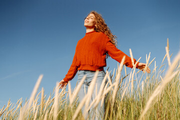 Beauty woman enjoying nature outdoors in tall grass. Calmness and tranquility. Travel, tourism...