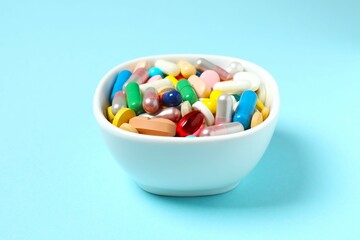 Various pills in a bowl on color background