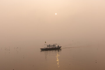 Tourists enjoying boat ride in the river ganges at varanasi during sunrise. Boatman sailing the...