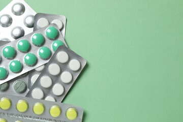 Pills in blister packs on green background, close up